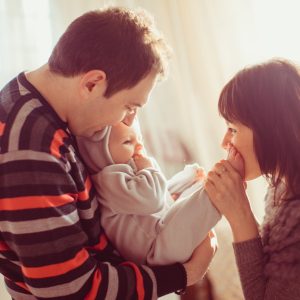 Mother kisses child's feet while father holds it